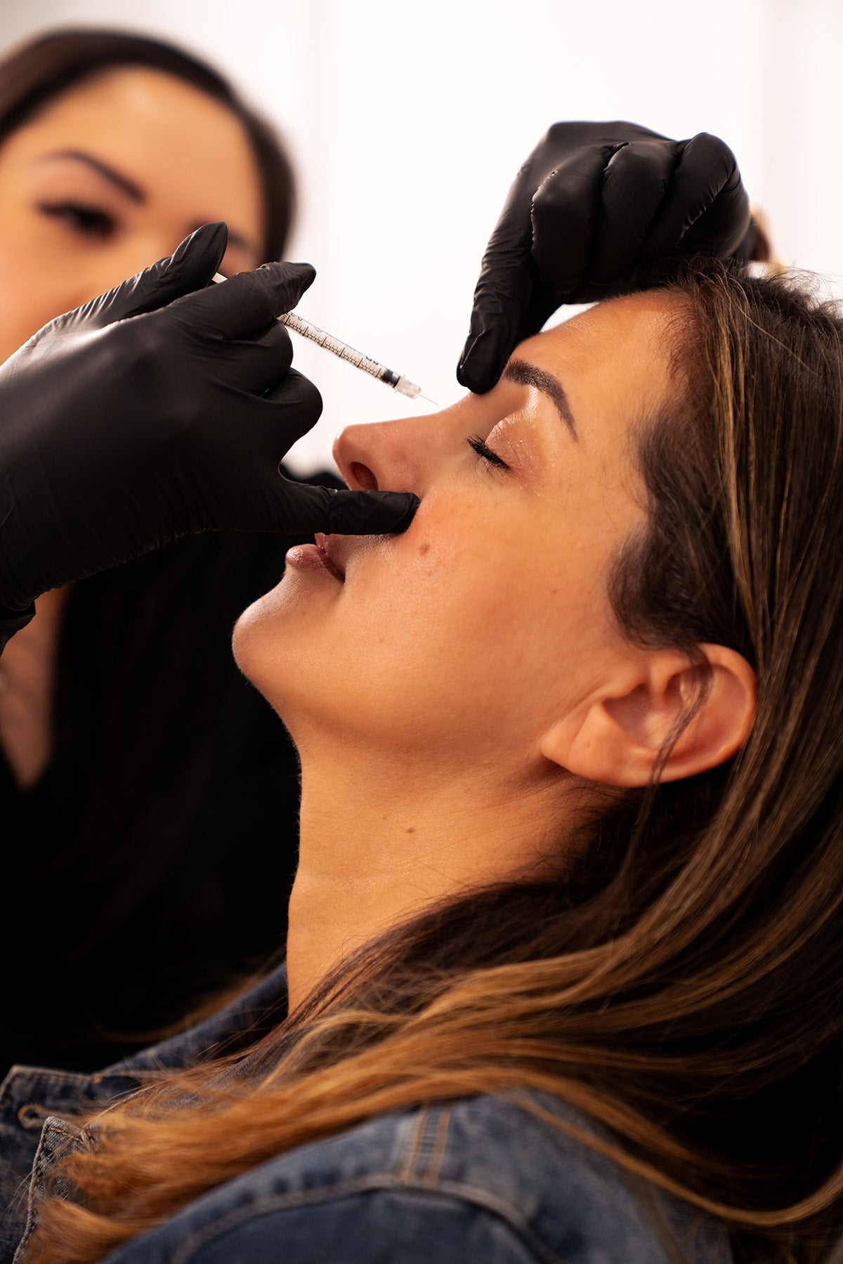 woman receiving a botox by a professional in black gloves.